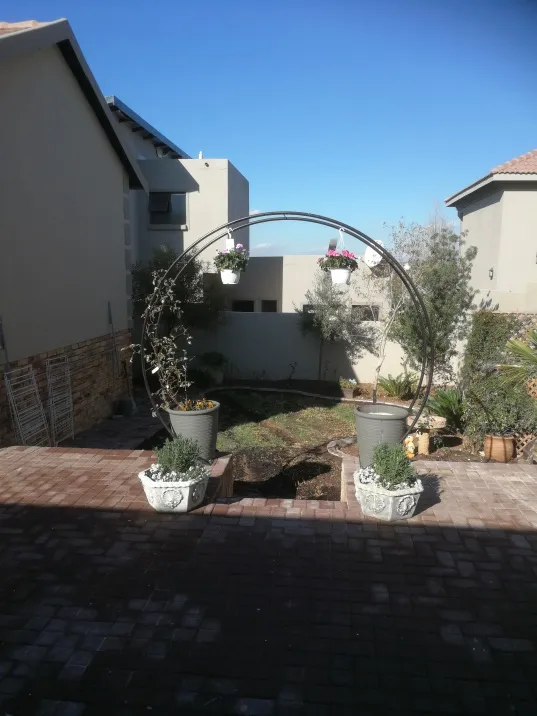 A round steel moon arch in a paved garden, with potted plants on either side